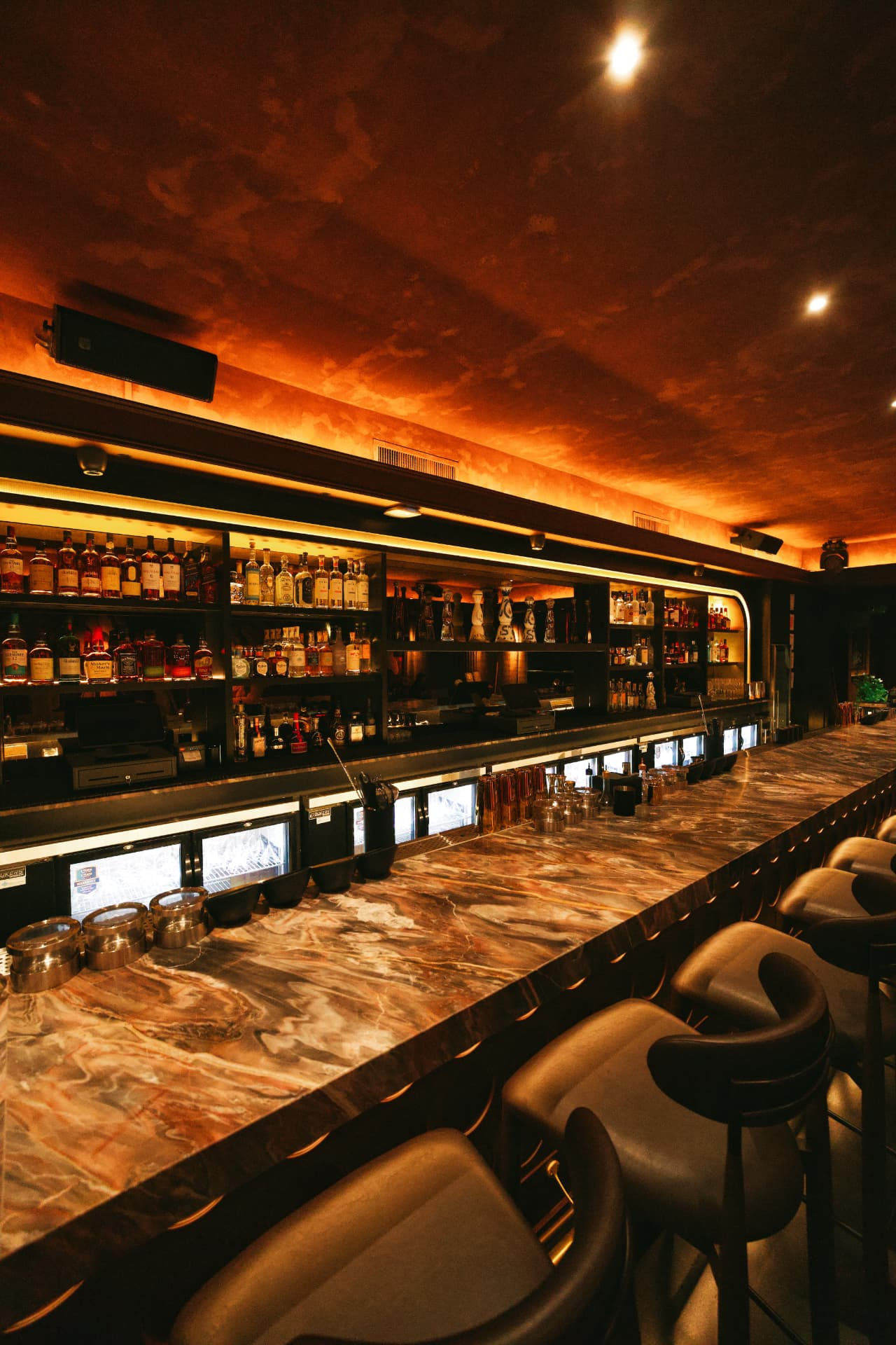 An amber-lit marble bar with warm copper tones