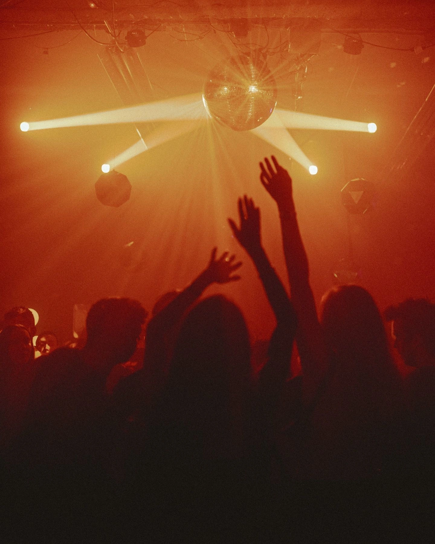 Hands raised under a disco ball on the dance floor